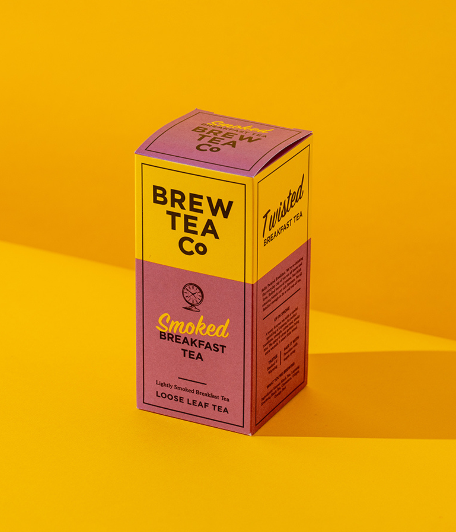 A box of Brew Tea Co Smoked Twisted English Breakfast Tea product shot is photographed on a yellow background. Lightly smoked breakfast tea blend with added citrus and spice.